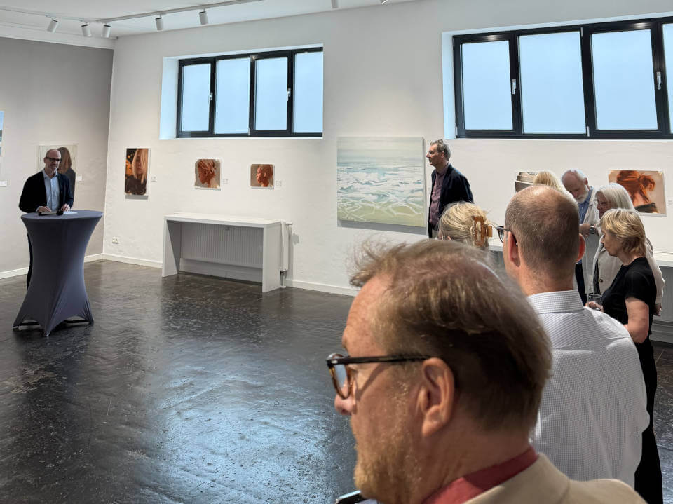 Blick in die gut besuchte Galerie RIECK bei einer Ausstellungseröffnung: Vortragssituation mit Publikum, zeitgenössische Gemälde an hellen Wänden und moderner Ausstellungsatmosphäre.
