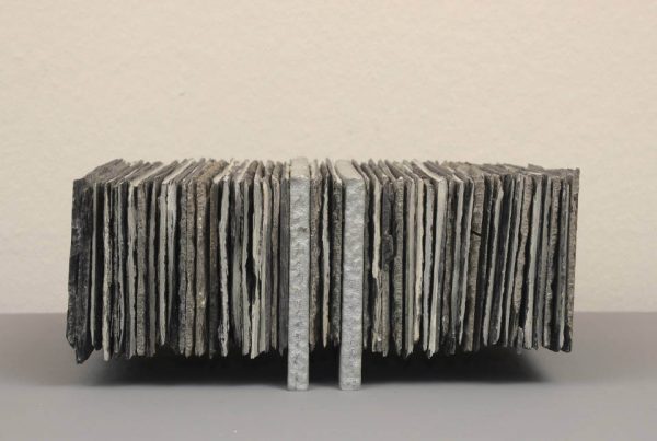 Assemblage „Schwebender Schiefer“ von Jens Chr. Jensen aus vertikal geschichteten Schieferplatten. Die skulpturale Objektkunst verbindet natürliche Materialien, Struktur und geometrische Ordnung.