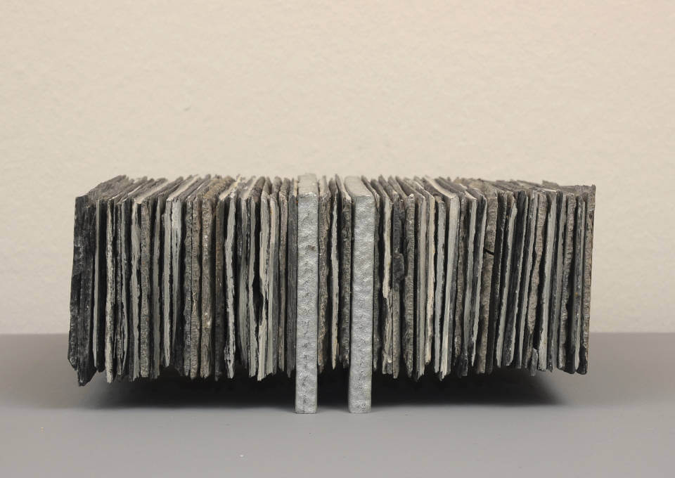 Assemblage „Schwebender Schiefer“ von Jens Chr. Jensen aus vertikal geschichteten Schieferplatten. Die skulpturale Objektkunst verbindet natürliche Materialien, Struktur und geometrische Ordnung.