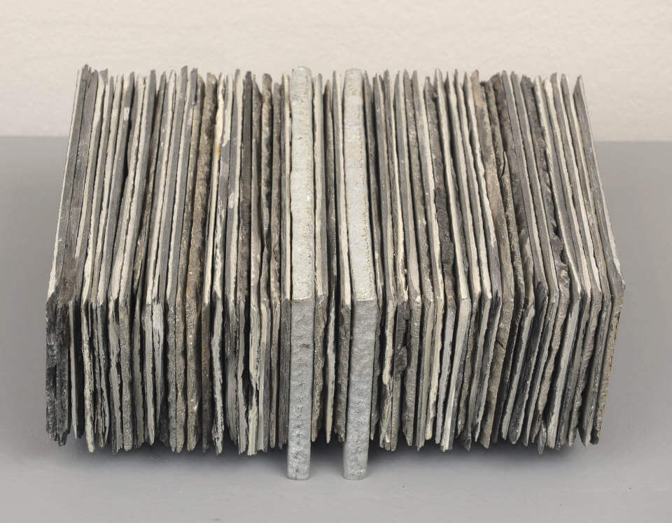 Assemblage „Schwebender Schiefer“ von Jens Chr. Jensen aus vertikal geschichteten Schieferplatten. Die skulpturale Objektkunst verbindet natürliche Materialien, Struktur und geometrische Ordnung.
