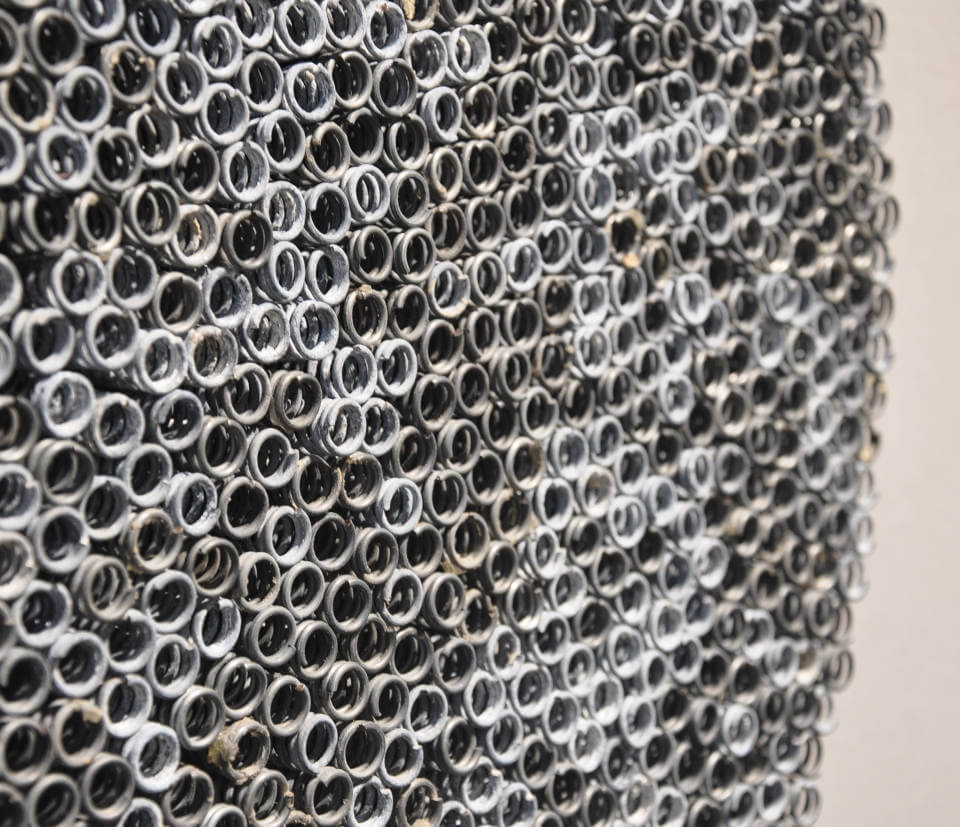 Detail der runden Assemblage „Spiralen“ von Jens Chr. Jensen aus hunderten röhrenförmigen Eisenfedern. Die monochrome Wandarbeit erzeugt eine faszinierende geometrische Struktur und optische Tiefe