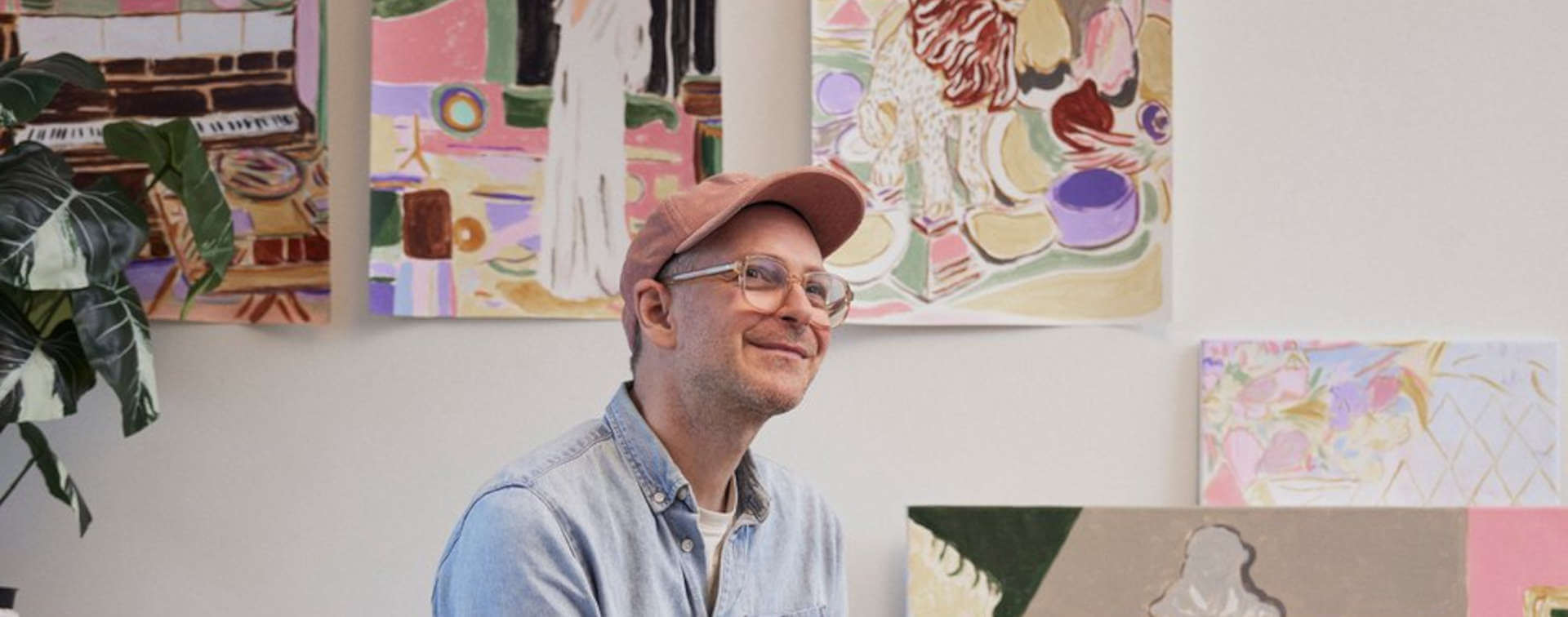 Atelieransicht mit sitzender Person - Mads Rafte Hein, farbenfrohen Gemälden, Interieur-Motiven, Pflanzen und Kunstwerken an der Wand