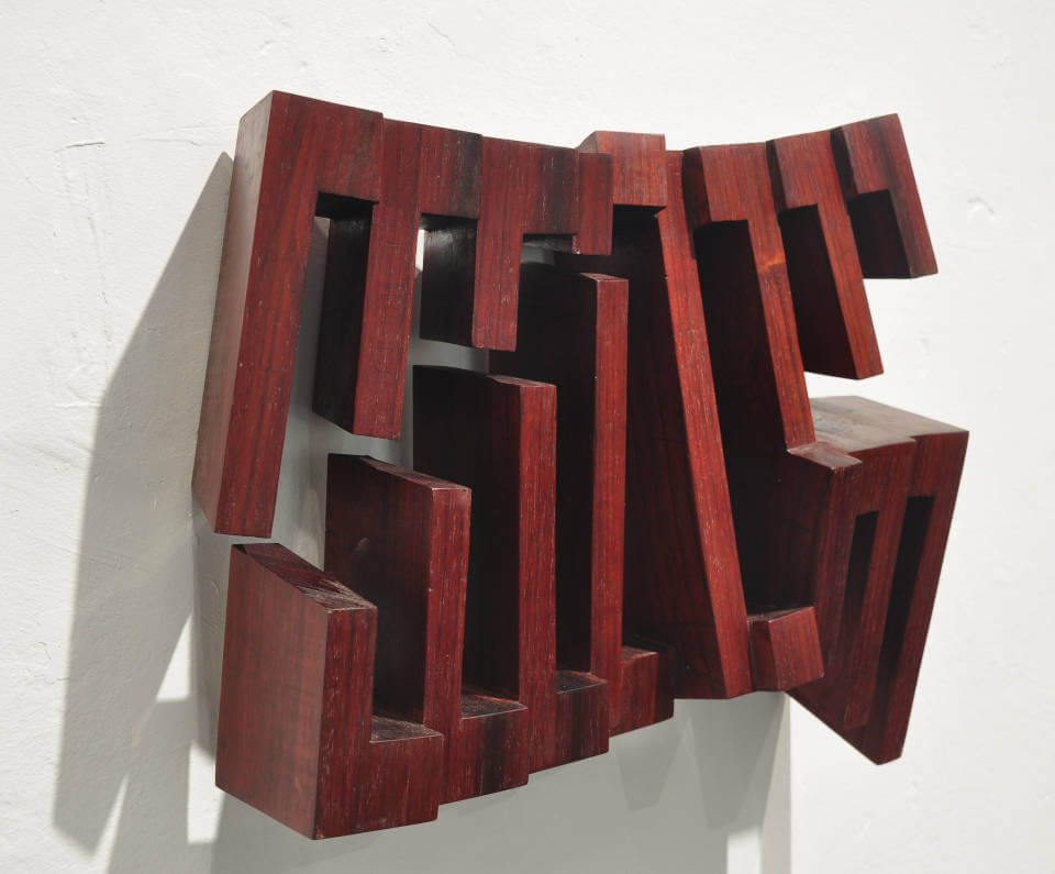 Wandobjekt „Fragiles Rot“ von Mathias Kadolph aus dunkelrotem Holz. Die geometrische Reliefskulptur erzeugt durch offene Strukturen, Tiefe und Schatten eine dynamische räumliche Wirkung.