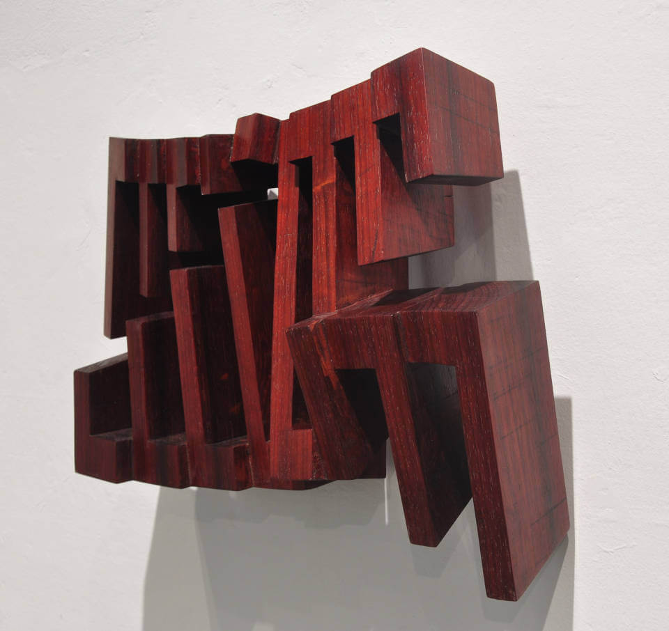 Wandobjekt „Fragiles Rot“ von Mathias Kadolph aus dunkelrotem Holz. Die geometrische Reliefskulptur erzeugt durch offene Strukturen, Tiefe und Schatten eine dynamische räumliche Wirkung.