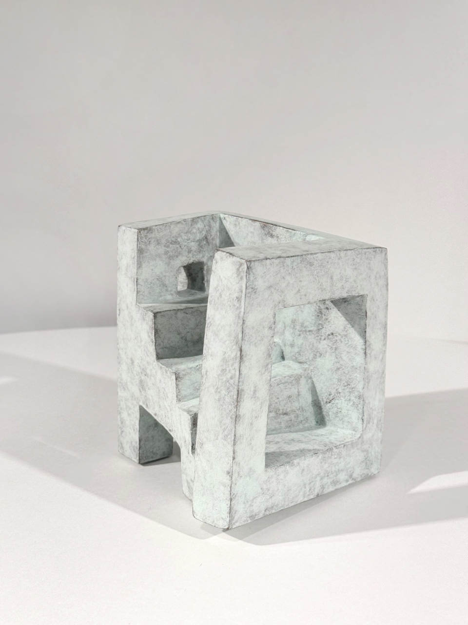 Abstrakte Skulptur „Teatro Piccolo“ von Mathias Kadolph mit architektonischen, geometrischen Formen und offenen Räumen in heller Steinoptik.