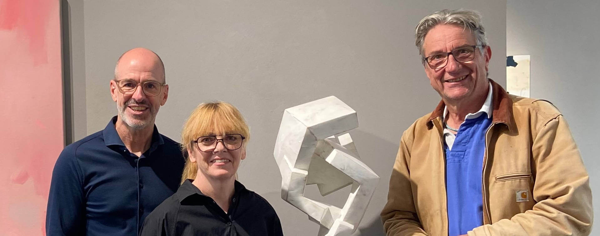 Steffi und Gordon Rieck mit Mathias Kadolph bei einem Künstlergespräch in der Galerie RIECK neben einer modernen abstrakten, weißgefassten Skulptur aus Holz