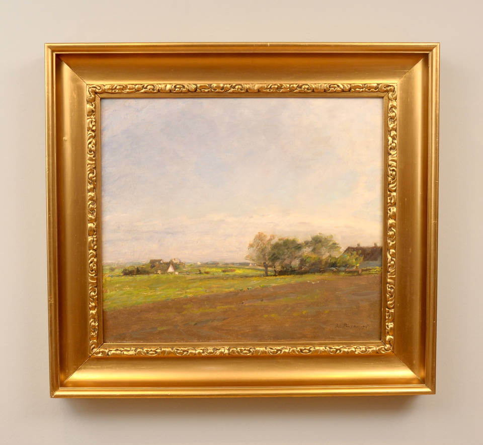 Sommerliche Landschaft von Julius Paulsen mit weiten Feldern, sanften Hügeln, einzelnen Bäumen und Häusern unter einem hellen, atmosphärischen Himmel mit goldenem Rahmen
